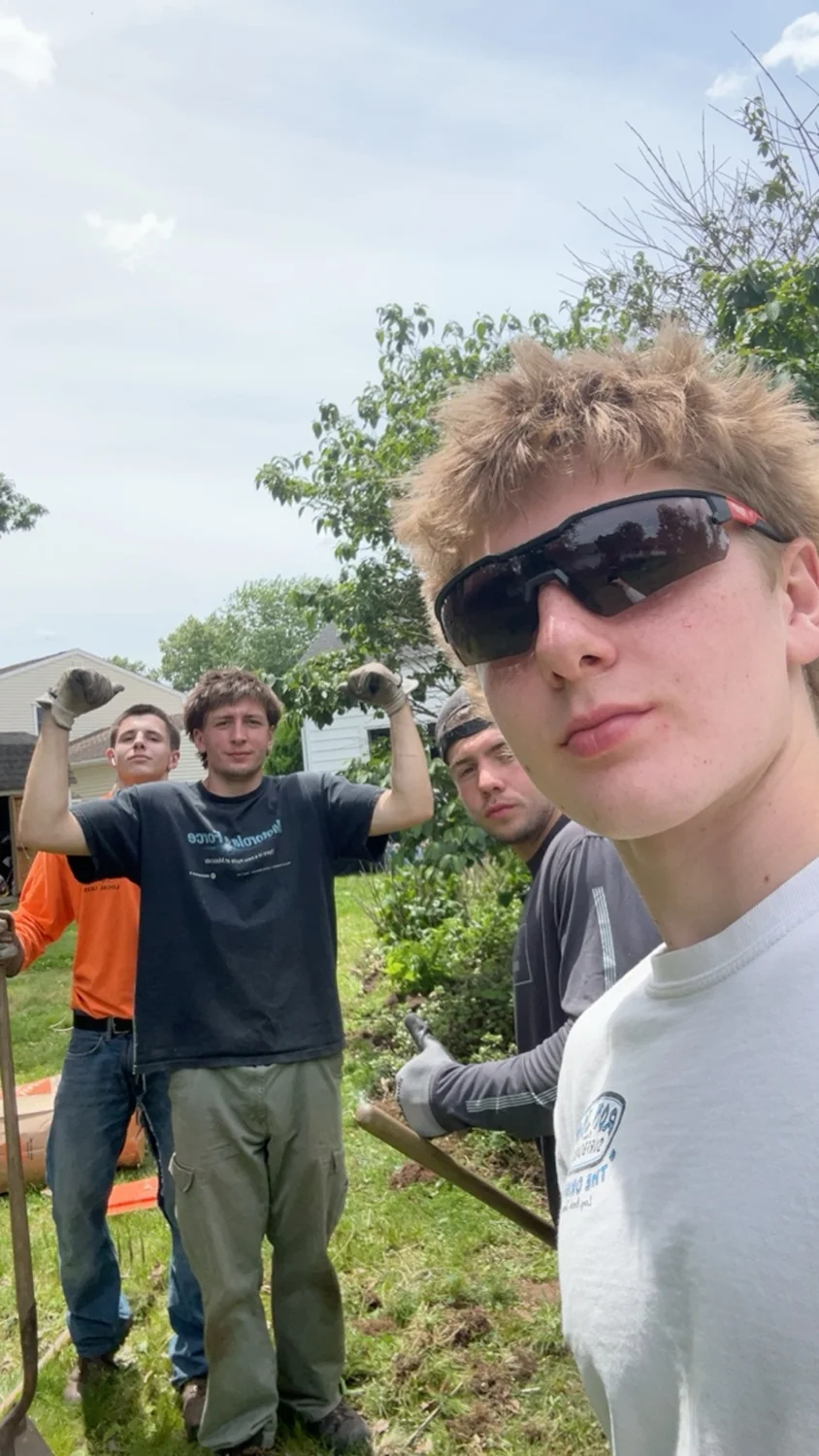 Crew members posing with work gloves and garden tools