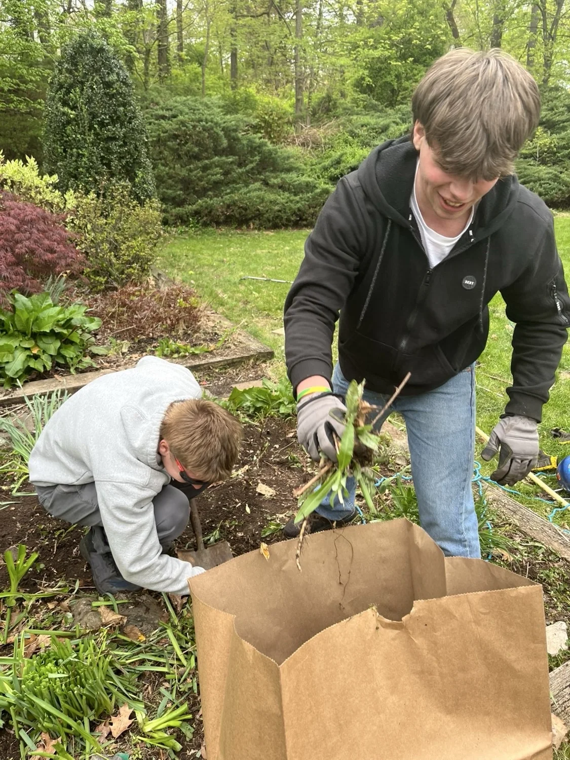 Crew members removing weeds and bagging garden debris