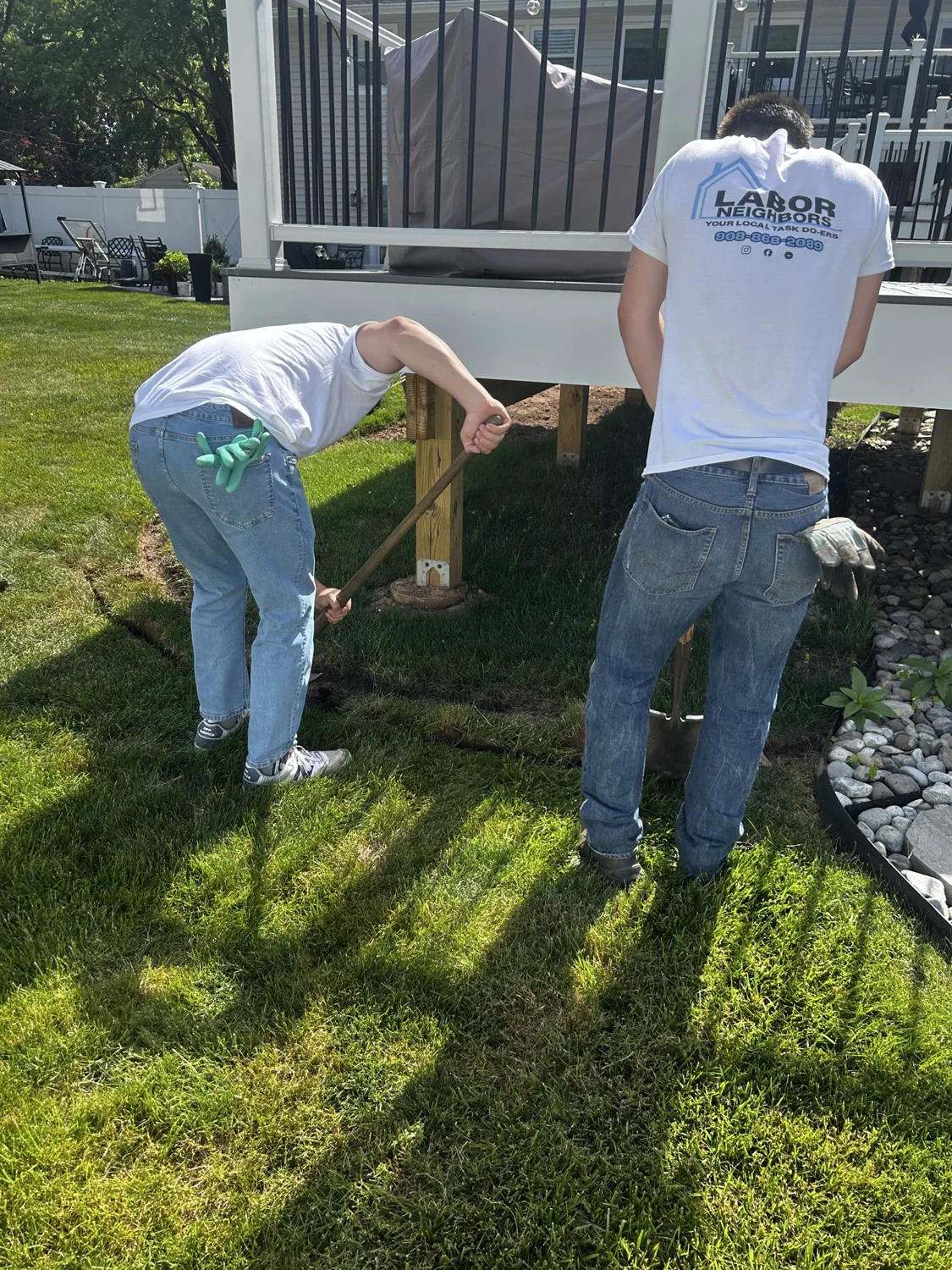 Two crew members digging beside a backyard deck