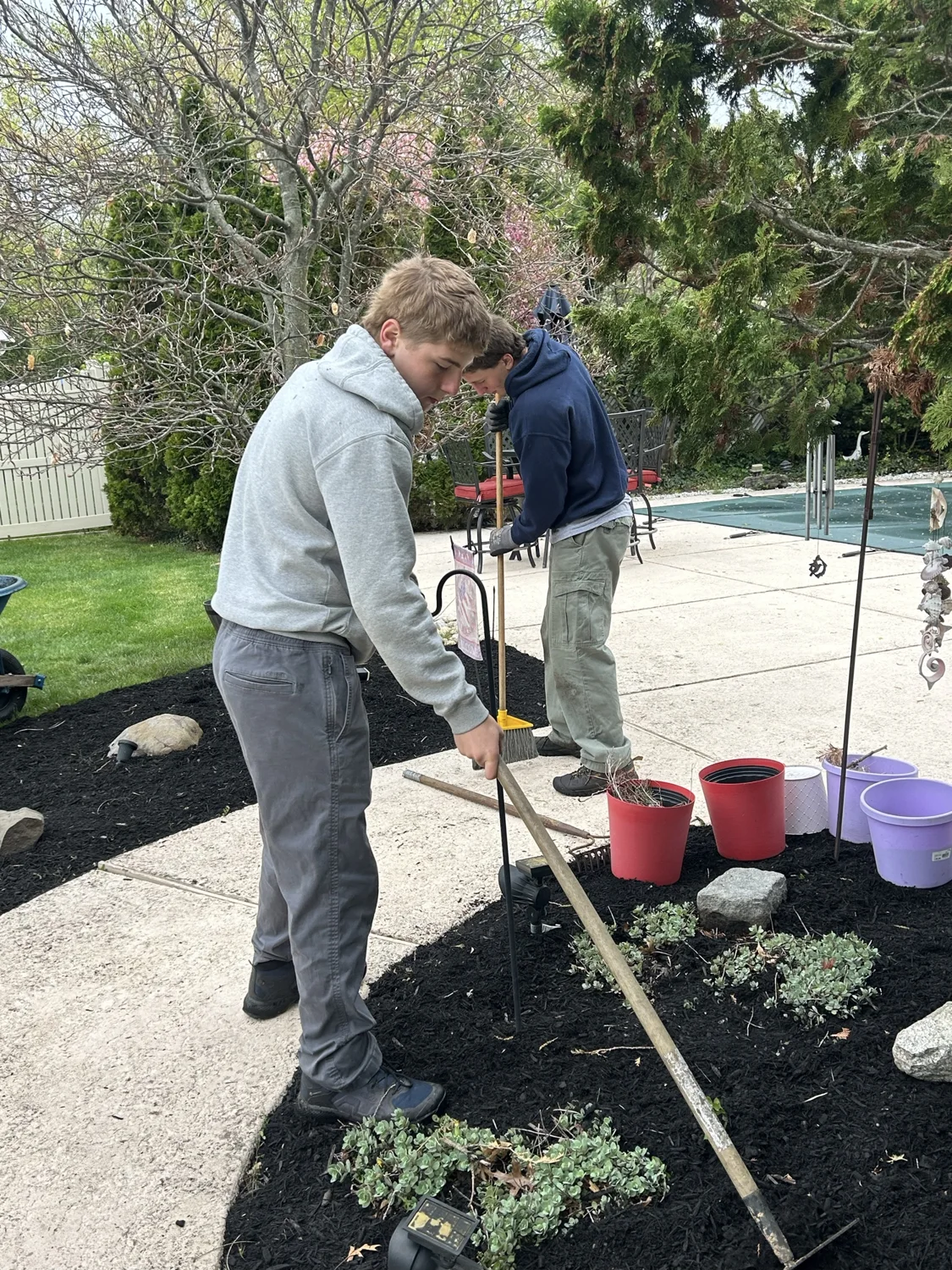 Crew members raking and tidying a mulched garden bed
