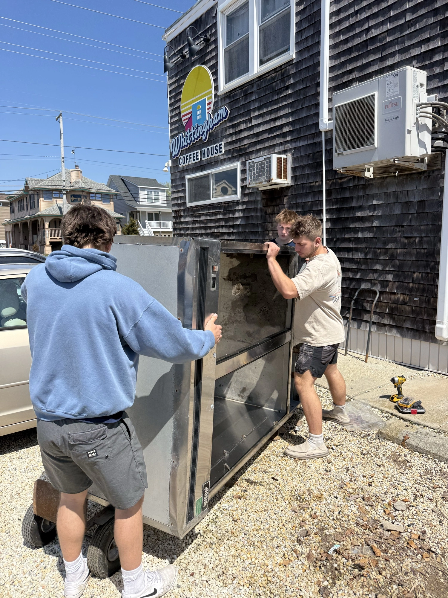 Three crew members working together to move a large metal unit outdoors