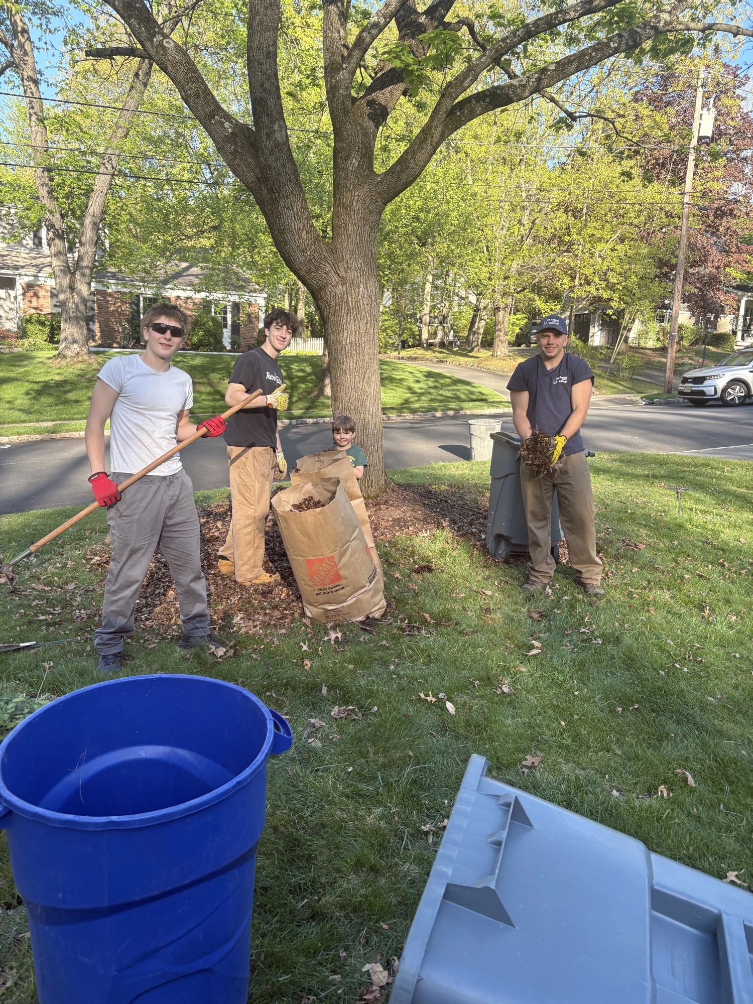 The crew gathering leaves and yard debris beside a neighborhood street